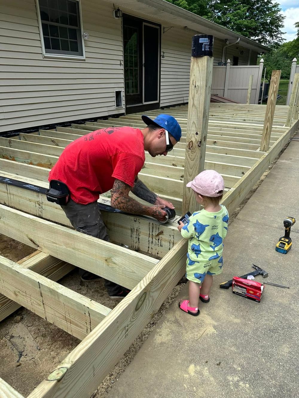 Man and child building a wooden deck frame, showcasing teamwork in construction.